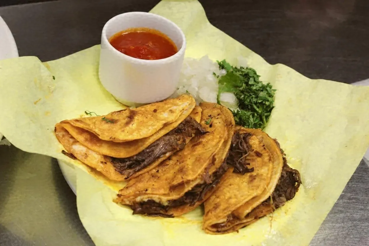Crispy tacos with a cup of red salsa